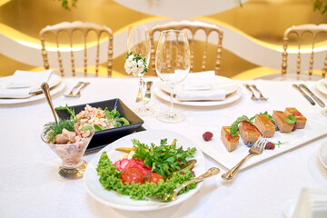 Table setting with blank guest card, plates with napkins and cutlery, copy space. Place setting at wedding reception. Table served for banquet in restaurant
