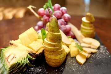 Plate with sliced fruits on servered buffet table at luxury wedding reception indoors, copy space. Catering banquet table in restaurant