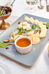 Cheese plate with honey and nuts on holiday dinner table, copy space. Wedding or birthday reception