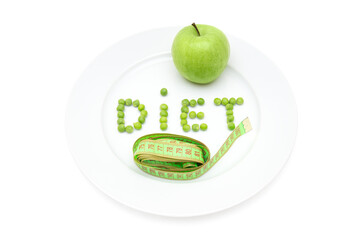 Word DIET made of garden peas on a large white plate, fresh green apple and a soft tape measure isolated on white. Detox, weight loss and dieting concept.