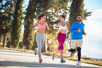 group of young people, two females and one male, jogging in beautiful region of italy, toscana, europe