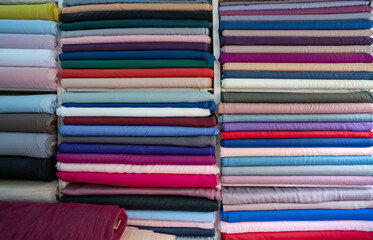 pile of colorful fabrics. haberdasher fabric shop choice of textile material in fabric market. Shelves with colorful fabric rolls. clothes in shop.