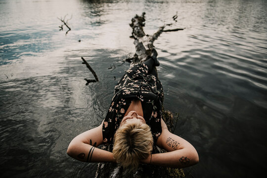 Europe, Germany, Berlin, Mueggelheim, Grosse Krampe, woman relaxing on a tree in the lake.