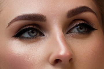 Elegance close-up female eye with dark brown eyeshadow. Macro shot of part of the face of a beautiful woman. Wellness, cosmetics and makeup. smooth beautiful eyebrows and eyelashes