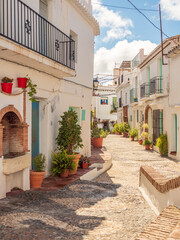 Fototapeta na wymiar Frigliana costa Del Sol Spain narrow streets winding between houses with colorful potted plants and cobbled road