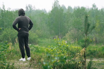 A man in a black tracksuit stands on mountain. The concept of outdoor sports in the morning.