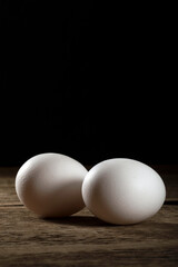 Two fresh white eggs on a wooden table.