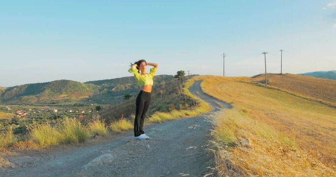 Ragazza con vestito giallo balla in un sentiero di campagna con pantaloni nero