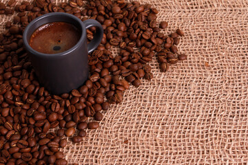 Black coffee grey cup, Arabica beans in bowl on jute burlap sackcloth. High angle, closeup, copy space. Coffee shop, morning, traditional roast concept