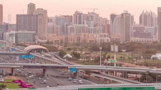 Dubai Golf Course with a cityscape of Gereens and tecom districts at the background aerial night to day transition timelapse. Traffic on sheikh zayed road with junction