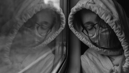 The girl is on the train. Sleeping girl in glasses and mask at the window in the train. The girl in the mask on a train during an outbreak of the coronavirus