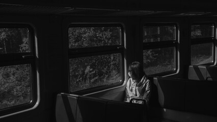 A girl in a medical mask rides a train and looks out the window