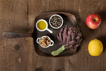 Ingredients for artichokes' salad with walnuts, pepper, apple, lemon and olive oil.