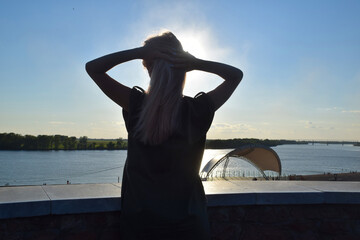 silhouette of woman with hands in head in front of river