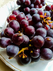 Grapes placed on a white plate having dark red color.