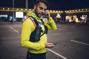 Night city fitness. Good looking man jogging on street.