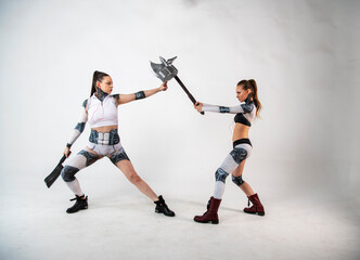 beautiful brunette girls in robotic costumes fight on battle axes and hammers