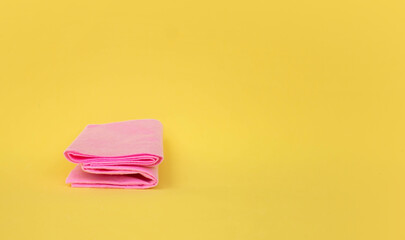 pink fabric on a yellow background and a clothespin. The concept of cleanliness and detergents