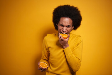 Fototapeta na wymiar Afroamerican biting into a juicy orange