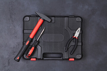 Labour day. Repair and renovation. Gift for man. Top view of toolbox, hammer, pliers and screwdriver on dark background