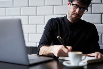 Cropped image of concentrated professional copywriter in eyeglasses writing advertising for personal website.Attractive smart  journalist making planning of working process in coworking space