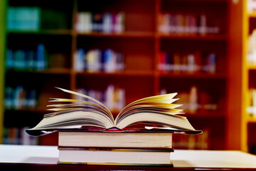 Open Book on wood table and blurred bookshelf in the library, education background, back to school concept.