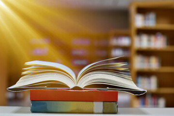 Open Book on wood table and blurred bookshelf in the library, education background, back to school concept.