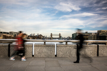 Motion blurred people walking with London River thames scene in background 