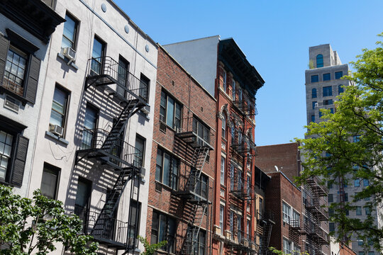 Row of Colorful Old Buildings with Fire Escapes on the Upper East Side of New York City with Green Trees