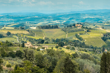 Fototapeta na wymiar Tuscan countryside with rolling hills, vineyards and farmhouses seen from a medieval hill town of San Gimignano, Province of Siena, Tuscany, Italy.