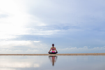 Fototapeta na wymiar Young woman practicing yoga outdoor on the beach in morning