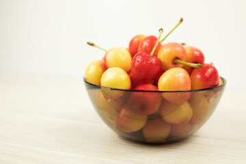 Ripe fresh sweet cherries in a transparent plate on a white background. Side view.