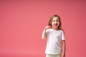 Cheerful little girl 4 years old, Caucasian, smiling, brushing her teeth