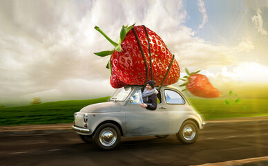 Frau im Kleinwagen transportiert reife Erdbeeren auf dem Dach