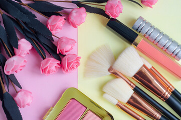Obraz na płótnie Canvas premium makeup brushes, blush and lipstick on a colored pink and yellow background, creative cosmetics flat lay