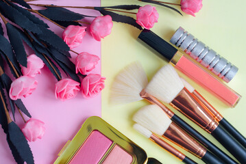 Obraz na płótnie Canvas premium makeup brushes, blush and lipstick on a colored pink and yellow background, creative cosmetics flat lay