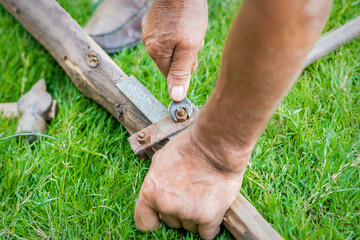 hand of an elderly man twisting the nut with a wrench outdoors. Repair by wrench.