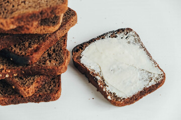 Sliced of brown bread with butter on a white wooden background. Top view. Copy, empty space for text