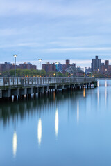 Naklejka premium Pier on a cloudy day with downtown Manhattan on the background from the east river 