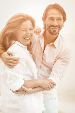 Happy man and woman laugh embracing each other. Romantic Caucasian couple hugging on white background outdoors. Tinted image.