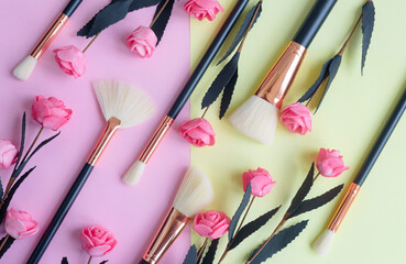 Obraz na płótnie Canvas premium makeup brushes and flowers on a colored pink and yellow background, creative cosmetics flat lay