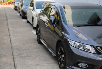 Closeup of front side of black car with  other cars parking in parking area beside the street in bright sunny day. 