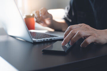 Man using mobile phone online working on laptop computer from home office