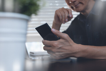 Asian man surfing  internet online working on mobile phone and laptop computer from home office