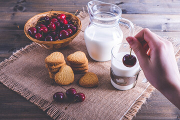 ripe cherries in hand and cookies on the table