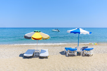 Empty sunbeds with umbrellas on Stegna beach (RHODES, GREECE)
