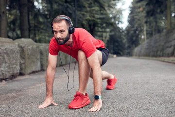 Sporty adult man making pause after jogging and exercising in the park.