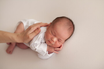 Sleeping baby boy in white clothes protected by a parental arm