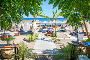 Umbrellas, sun beds and holiday-makers on Stegna beach (RHODES, GREECE) - obrazy, fototapety, plakaty