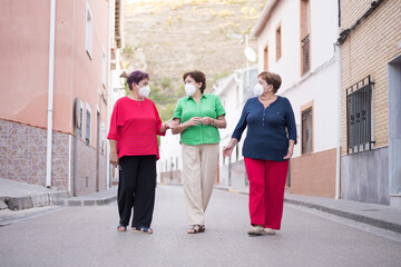 Obraz premium 3 older women with face mask on the street and one of them looking at the camera